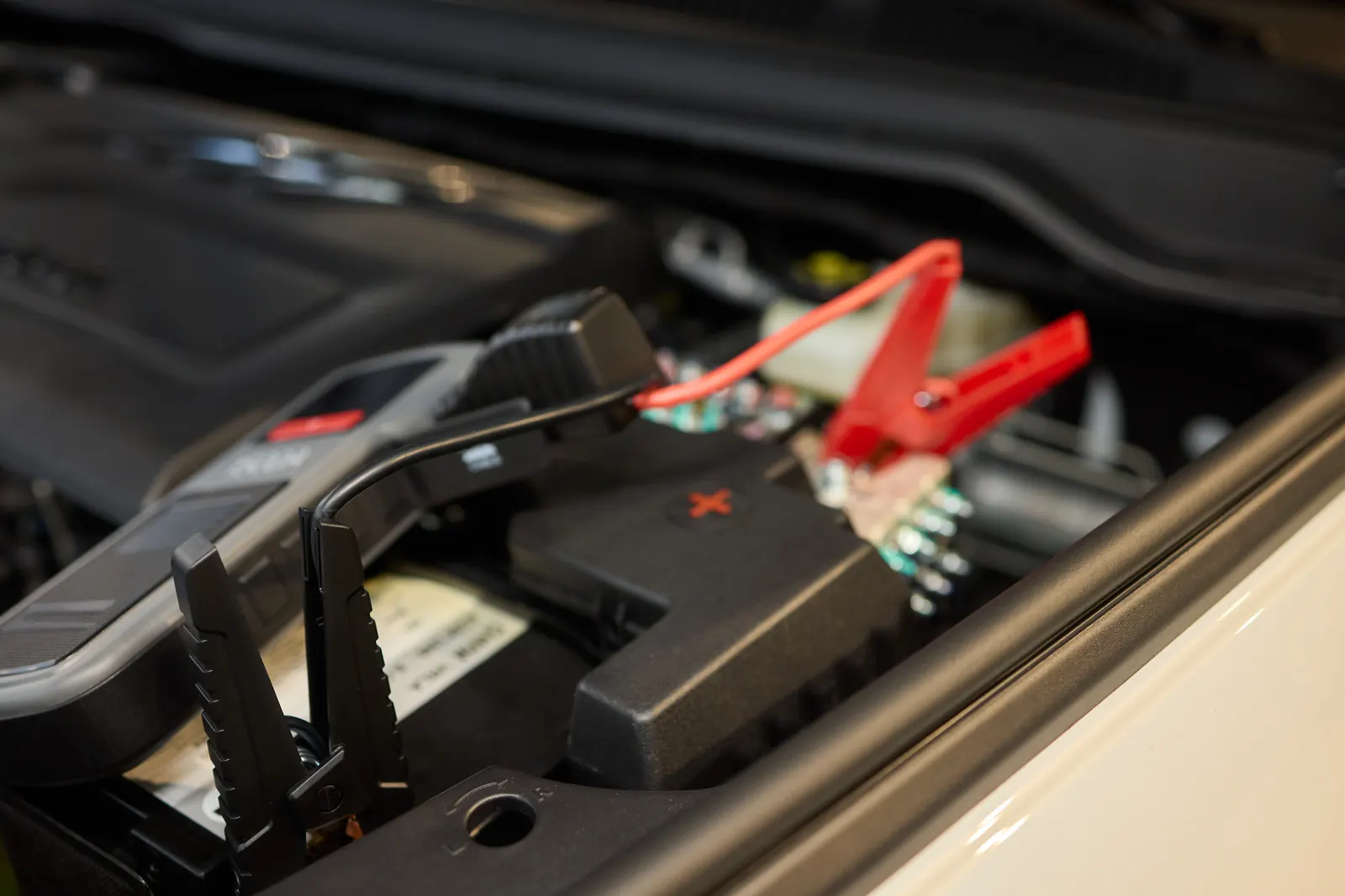 Car battery connected to jumper cables under the bonnet