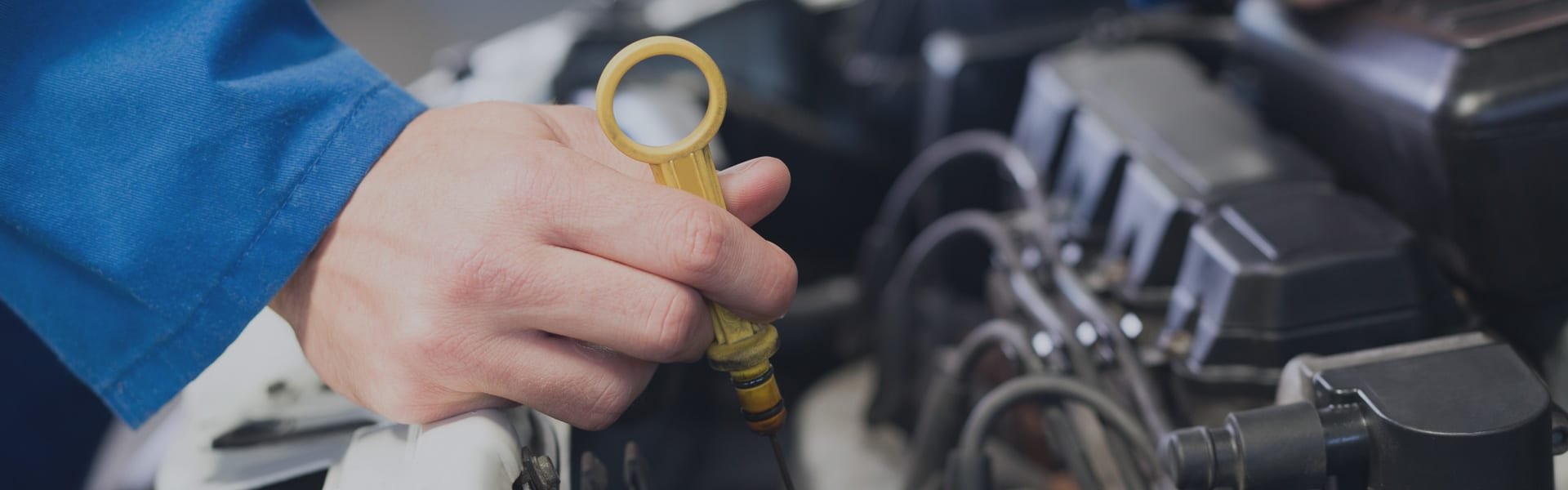 Mechanic checking the engine oil dipstick during a car service